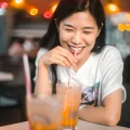 A girl is smiling while drinking ice limau at mamak